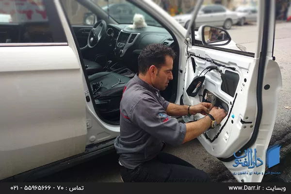 یکی از شاگردان موسسه درالفنون در حال یادگیری تعمیر سیم کشی داخل درب خودرو